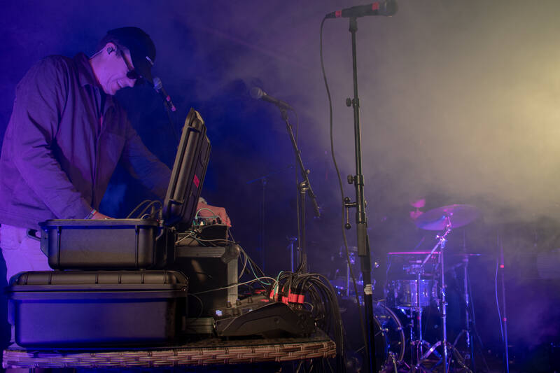 Andreas opening a flight case on stage, drums in the haze behind
